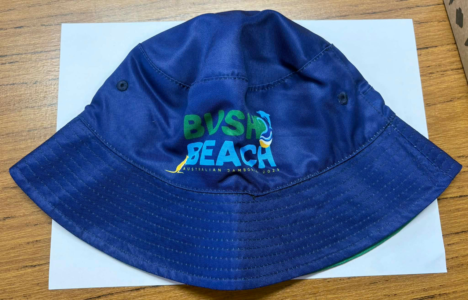 Blue bucket hat with Girl Guides Australia logo with a green reversible side with a kangaroo and dolphin pattern