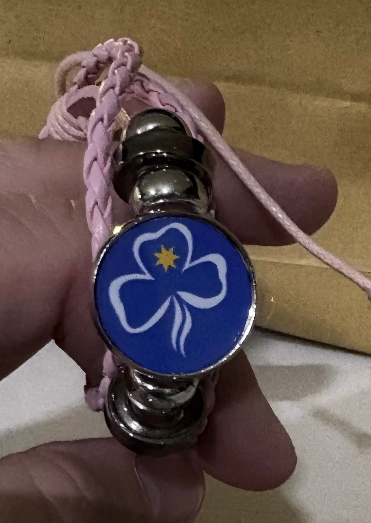 A faux leather bracelet with a disc with the trefoil 