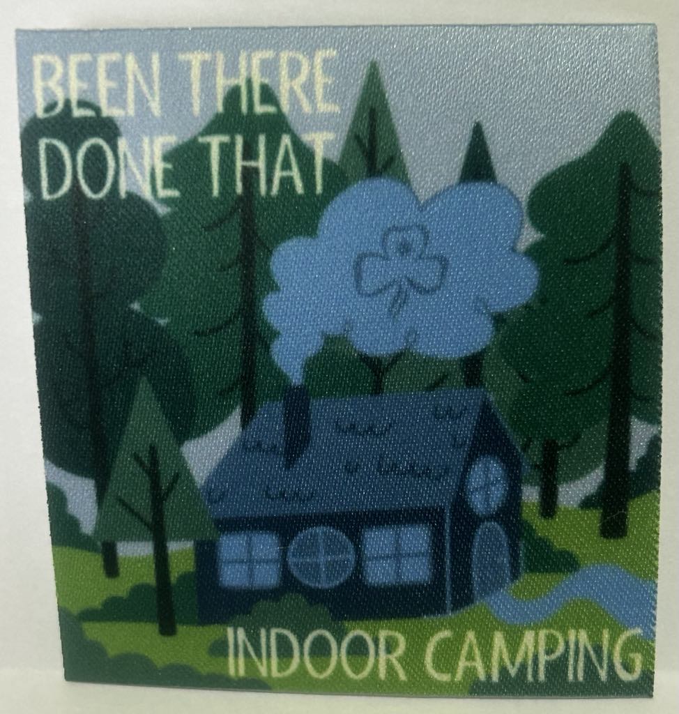 a square unbound badge that has a cabin in the woods with smoke coming from the chimney with the words been there done that indoor camping in white