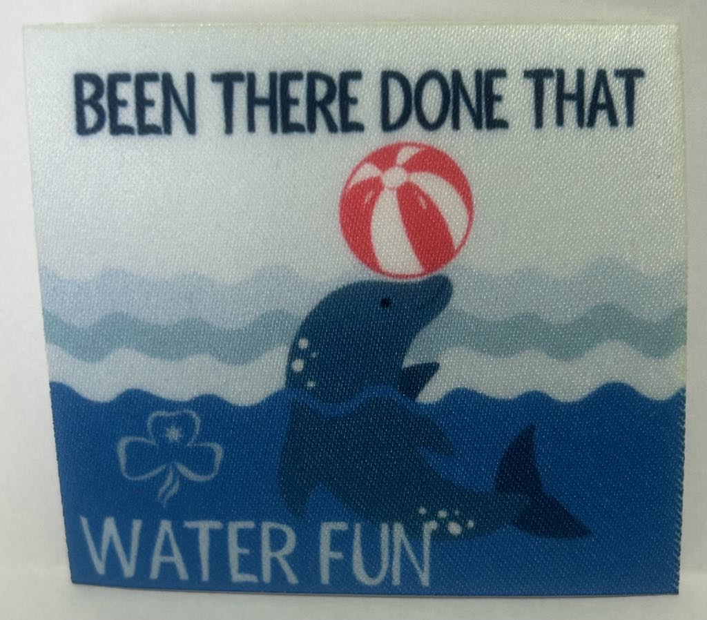 a square unbound badge with a dolphin in the water with a ball on it's nose with the words been there done that water fun in blue