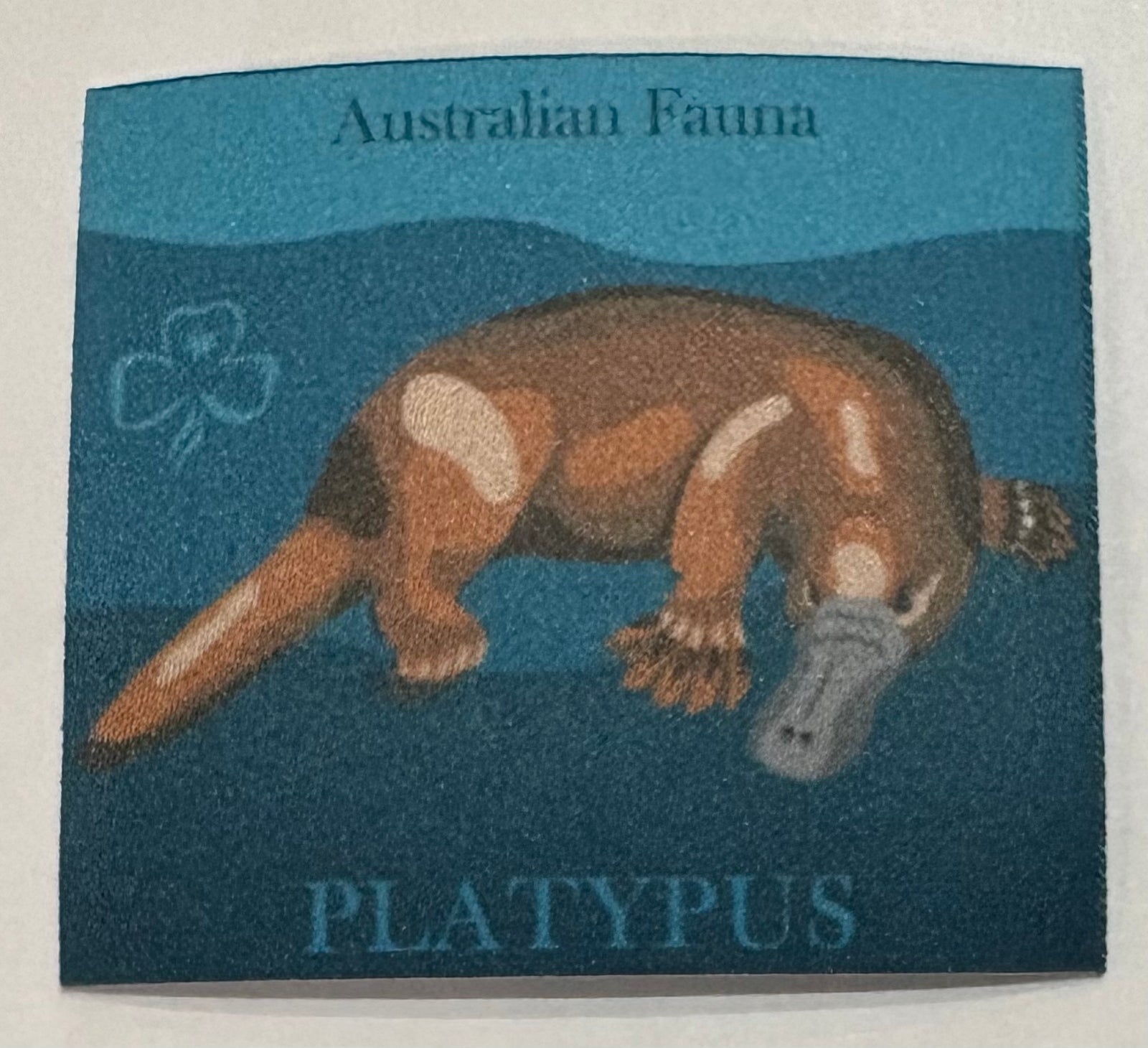 A square unbound badge in shades of blue with a platypus 