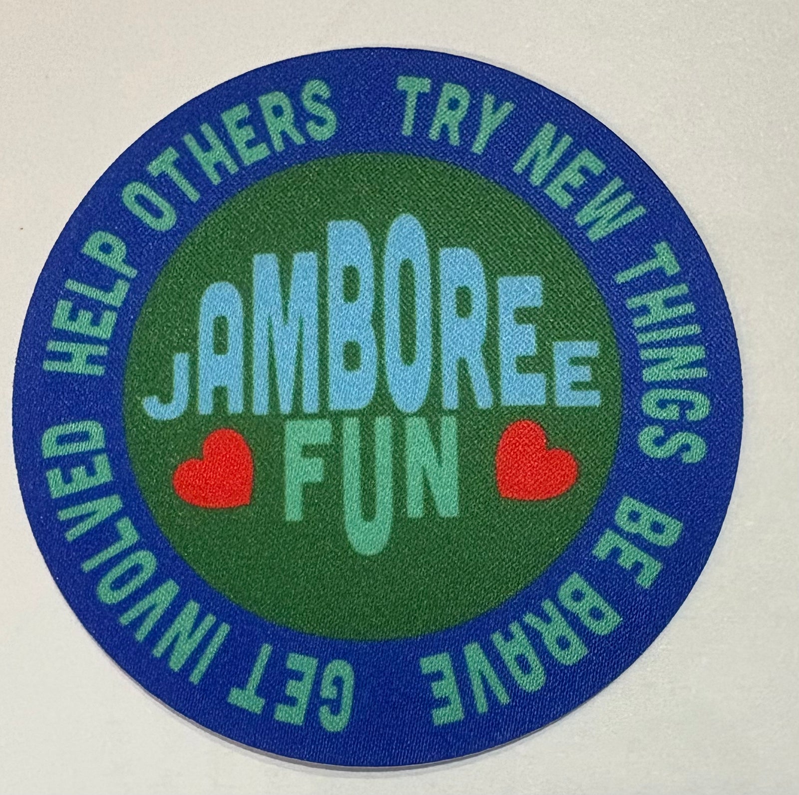A round unbound green and blue badge with jamboree fun and hearts
