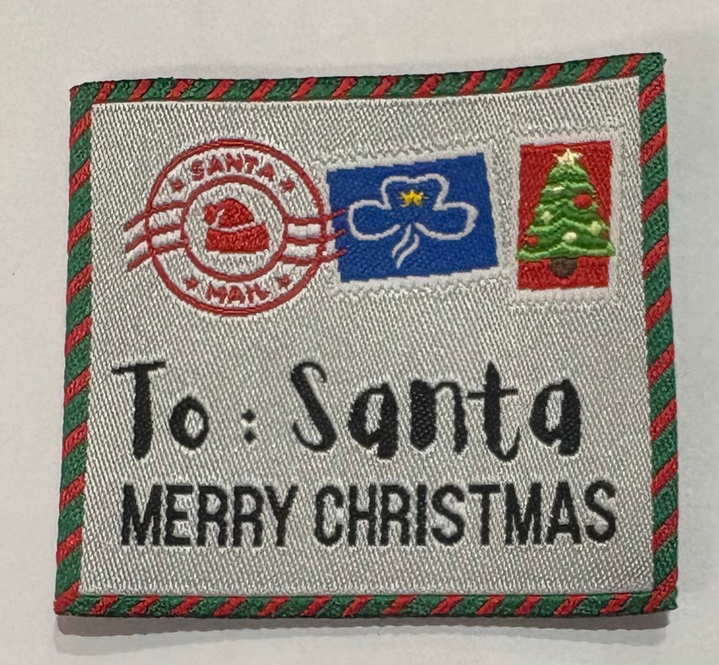 A square unbound badge with red and green around the edges with to Santa Merry Christmas and some stamps 