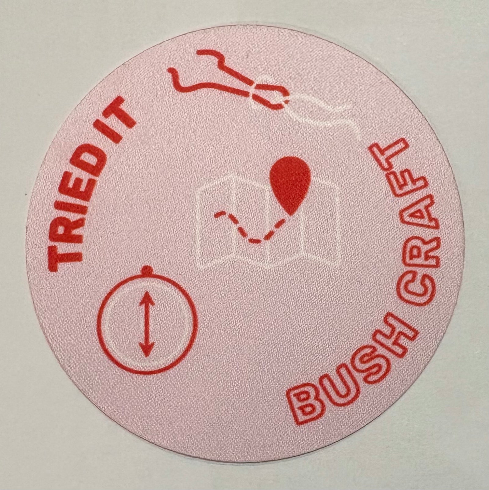 A round light pink badge with a compass and map on it