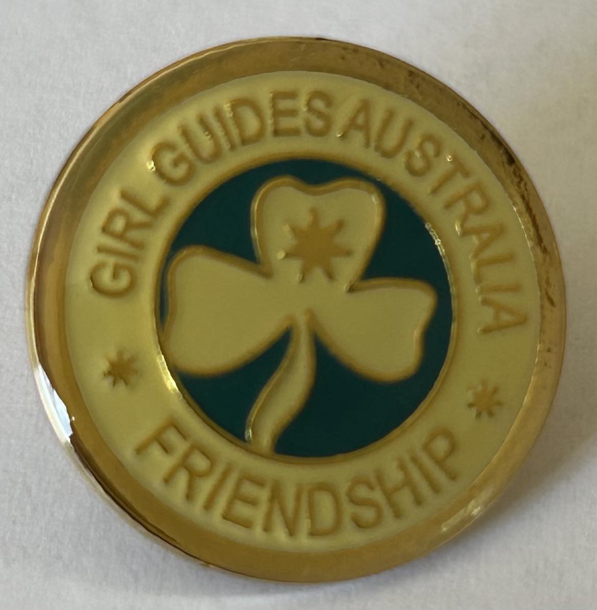 a round metal pin with the trefoil in the centre and girl guides Australia friendship written around the outside
