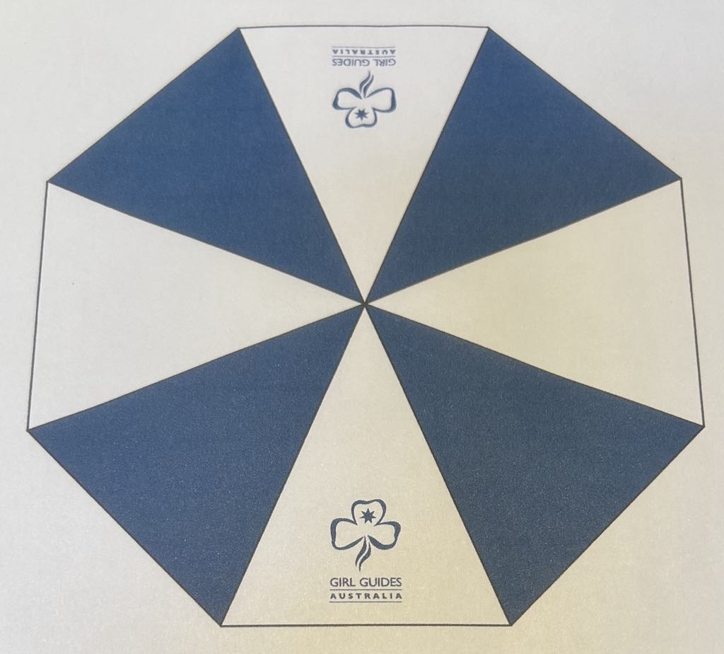 a blue and white umbrella with a trefoil and girl guides Australia printed on it
