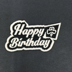 bound badge that says happy birthday in white that glows green in the dark