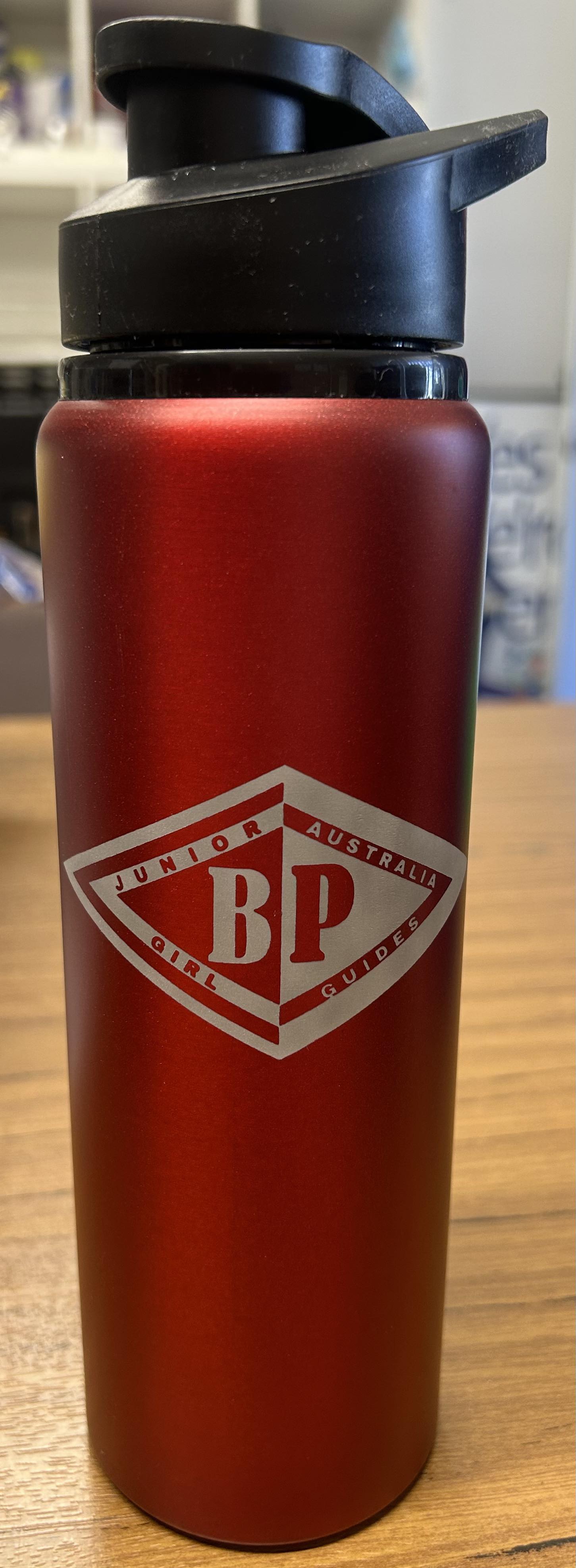 a red aluminium drink bottle with the the Junior BP emblem on the front
