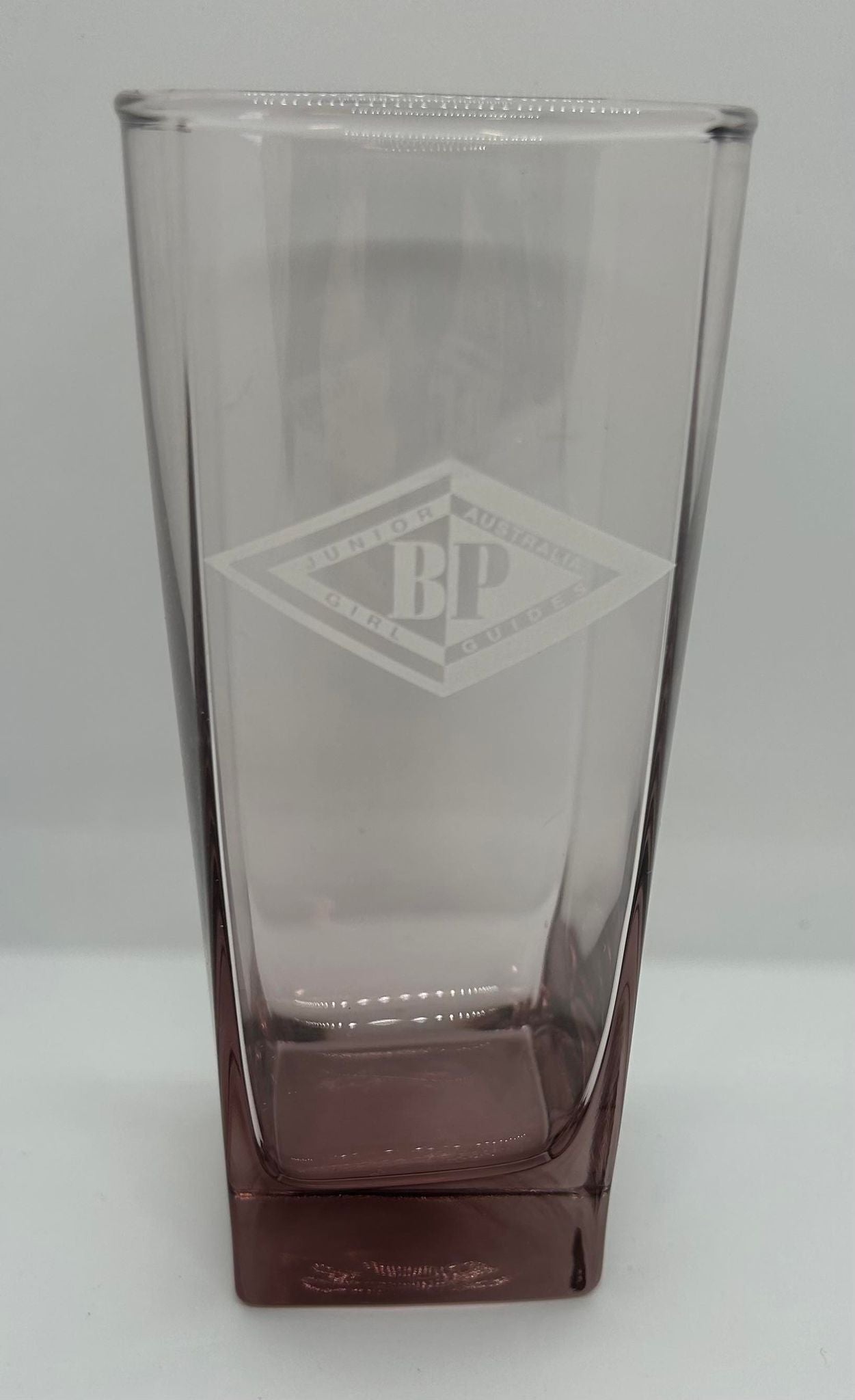 a clear glass with a mauve Botton with the junior BP award symbol etched onto the front