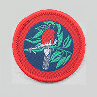 a round badge bound in red with a red robin on it