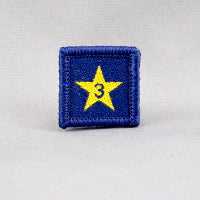 square blue badge with a gold star with the number three in the centre written in blue
