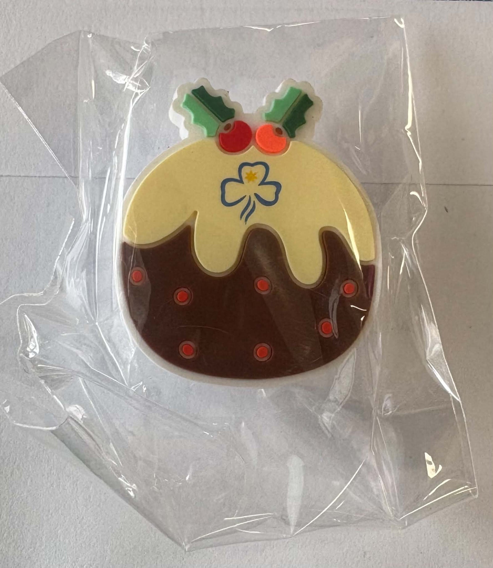 a round croc charm in the shape of a round Christmas pudding with icing and a trefoil