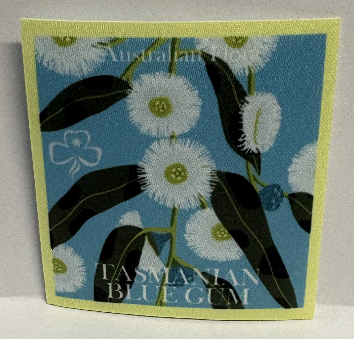 Square unbound badge with Tasmanian Blue Gum design featuring white flowers and green leaves on a blue background.