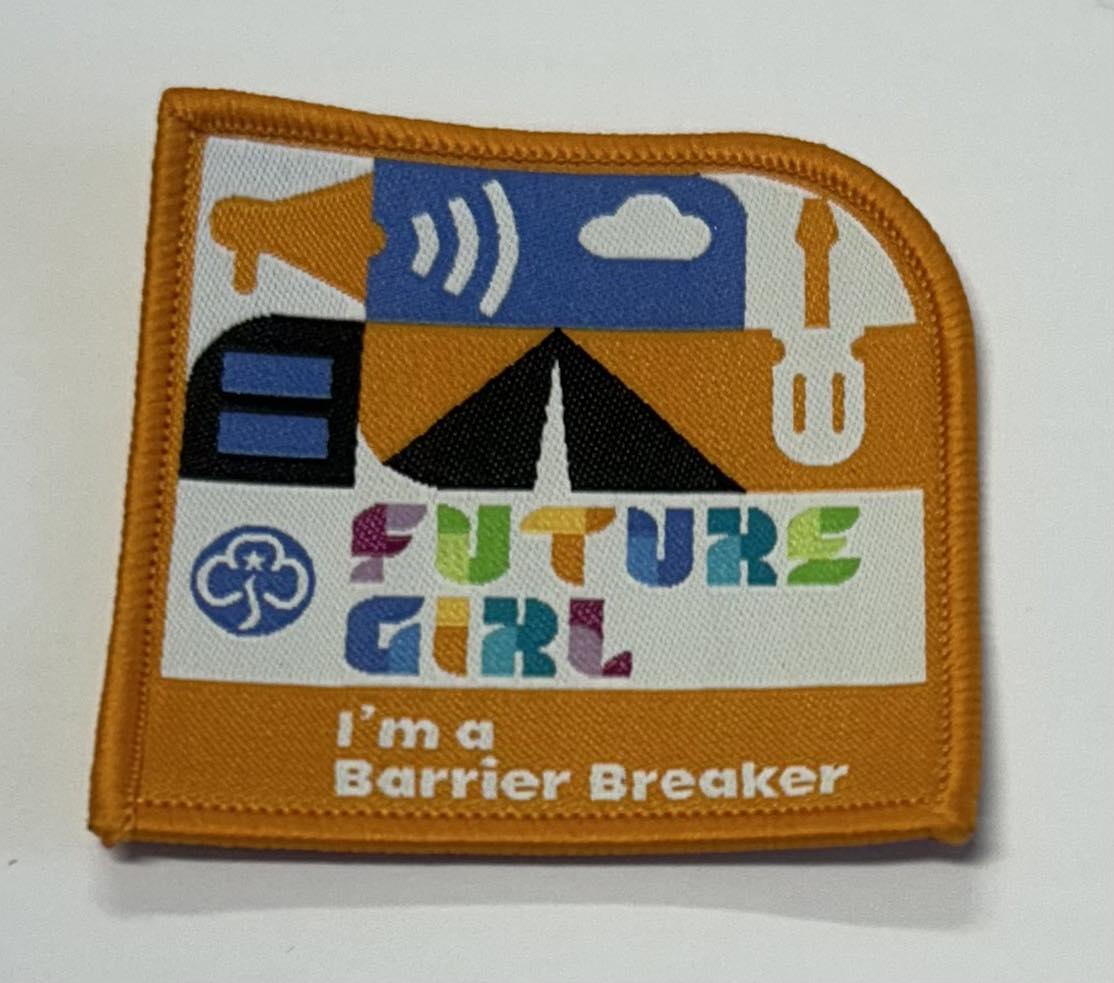 a square badge bound in orange with the words future girl I'm a barrier breaker with a tent, screwdriver and wifi symbol