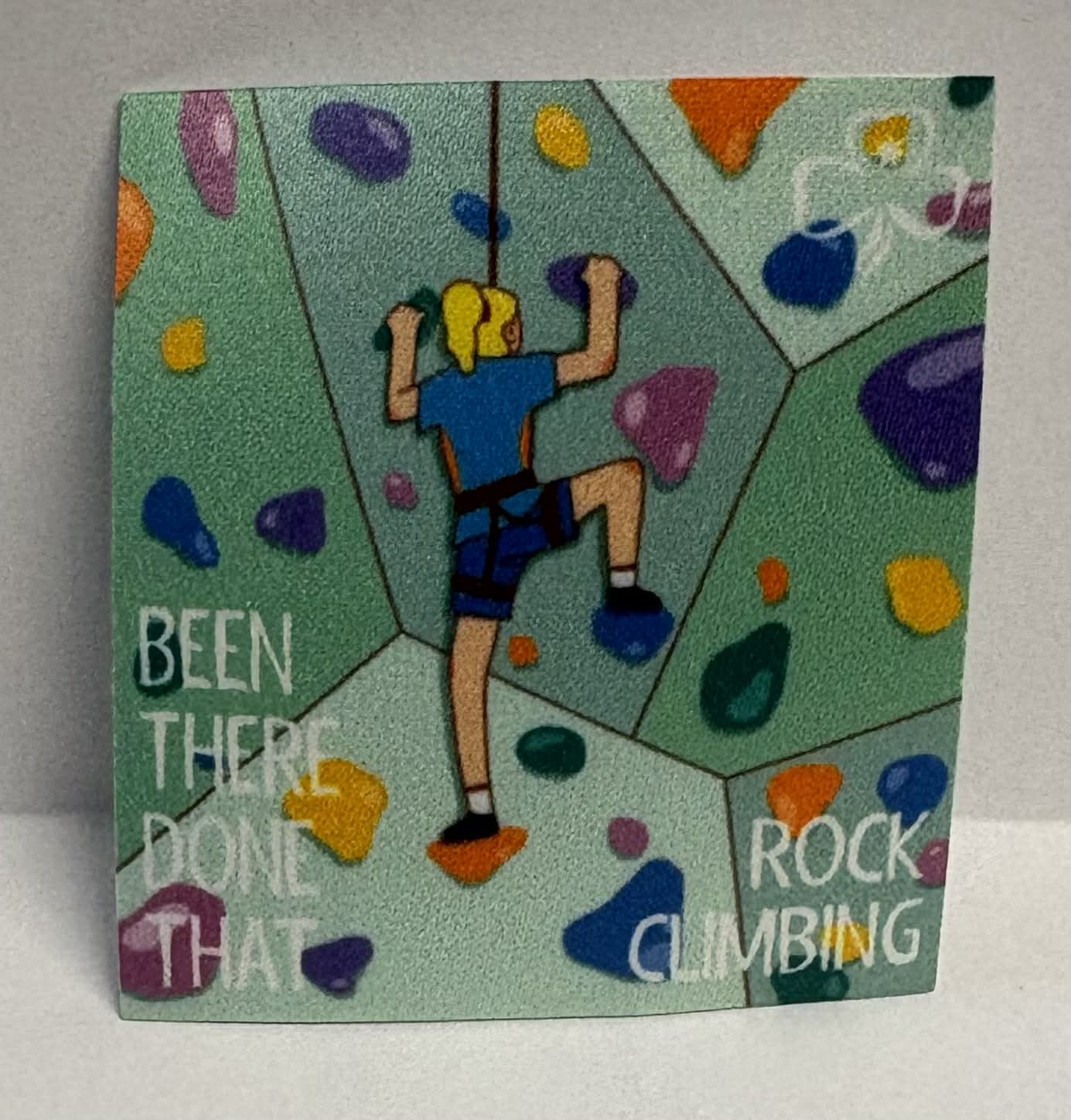 Square unbound badge with a rock climber design and text 'Been There Done That Rock Climbing' on a green background.