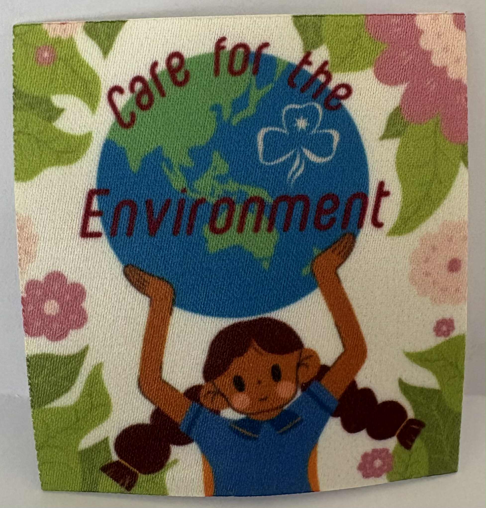 a square unbound badge with a child holding the Earth, text 'Care for the Environment', and floral design.