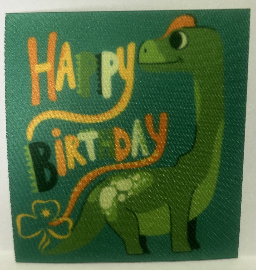 a square unbound badge with a green background with a dinosaur with the words happy birthday