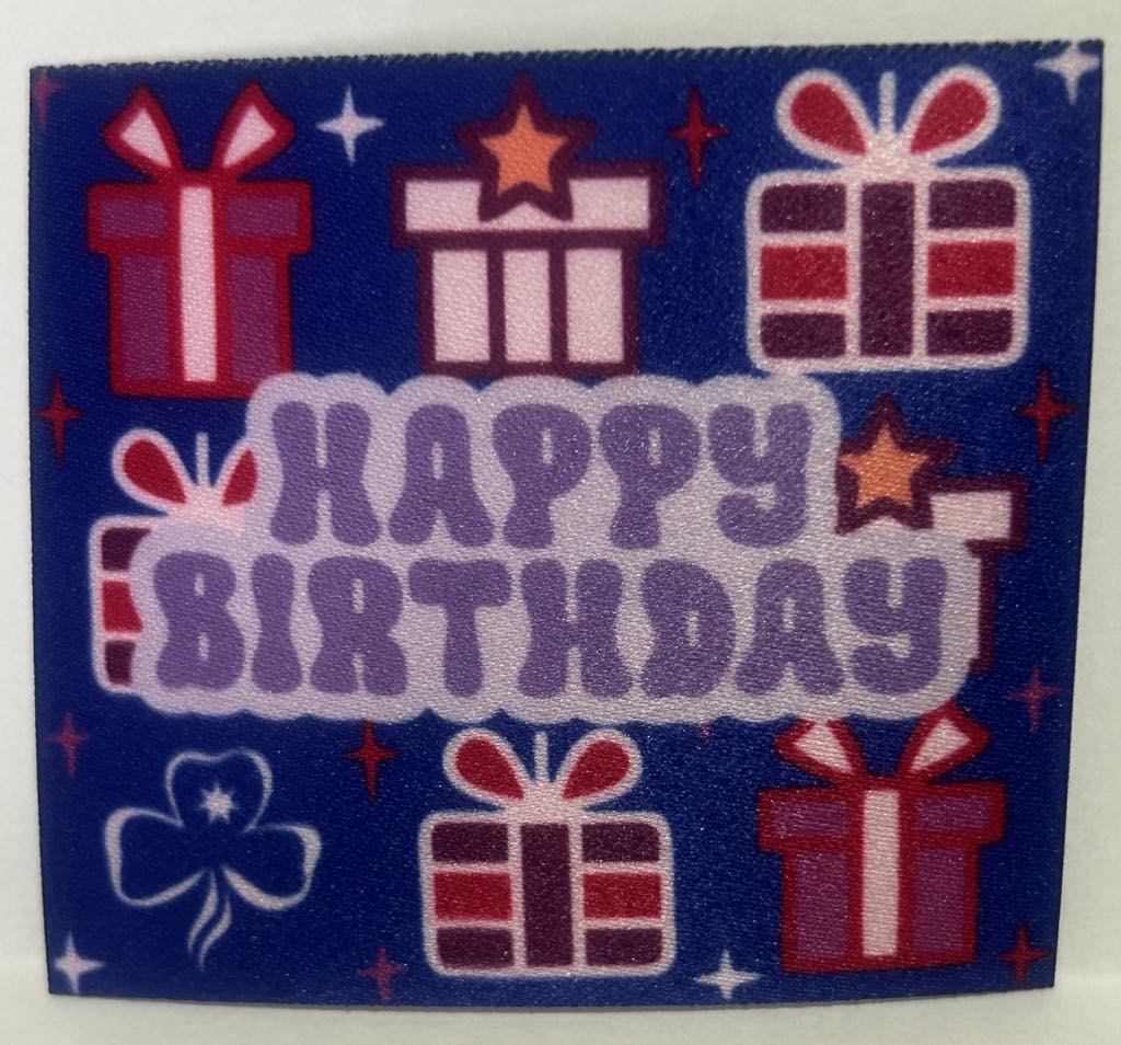 a square unbound badge that has a blue background with presents in different shades of purple and the words happy birthday in light purple in the middle