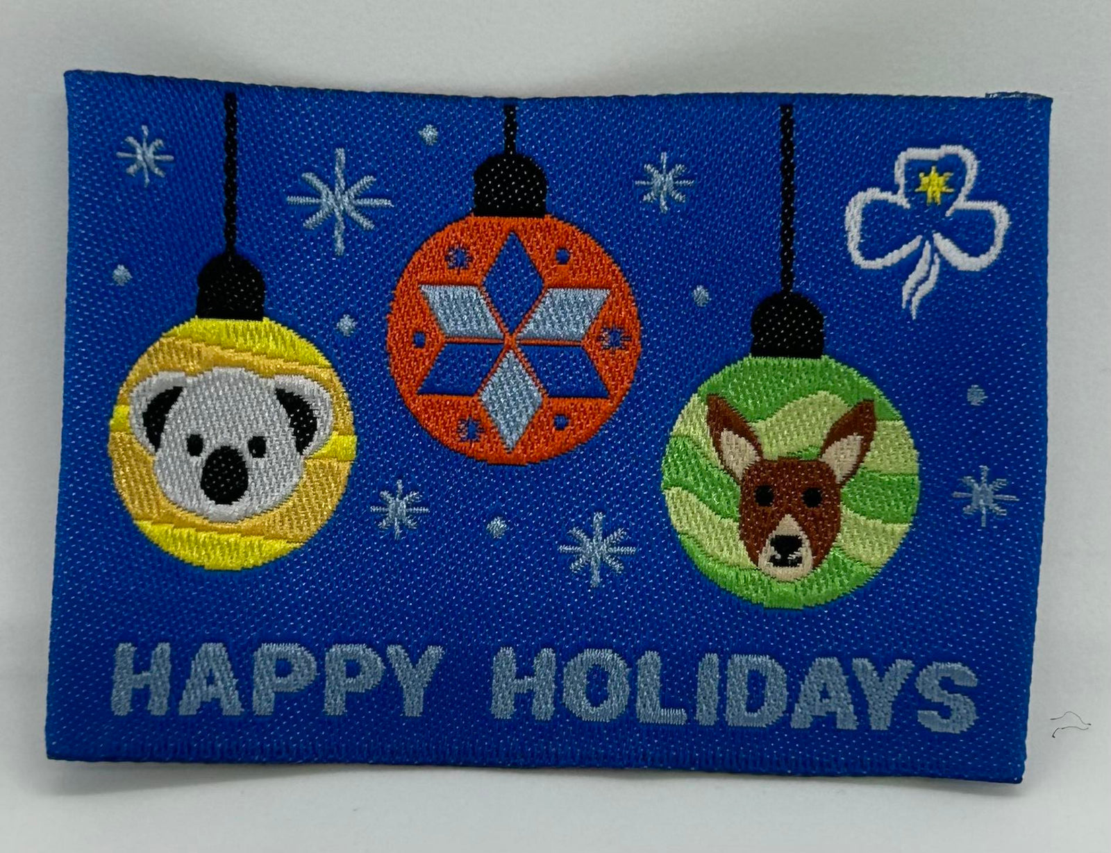 a square unbound badge that is blue in colour with three Christmas baubles