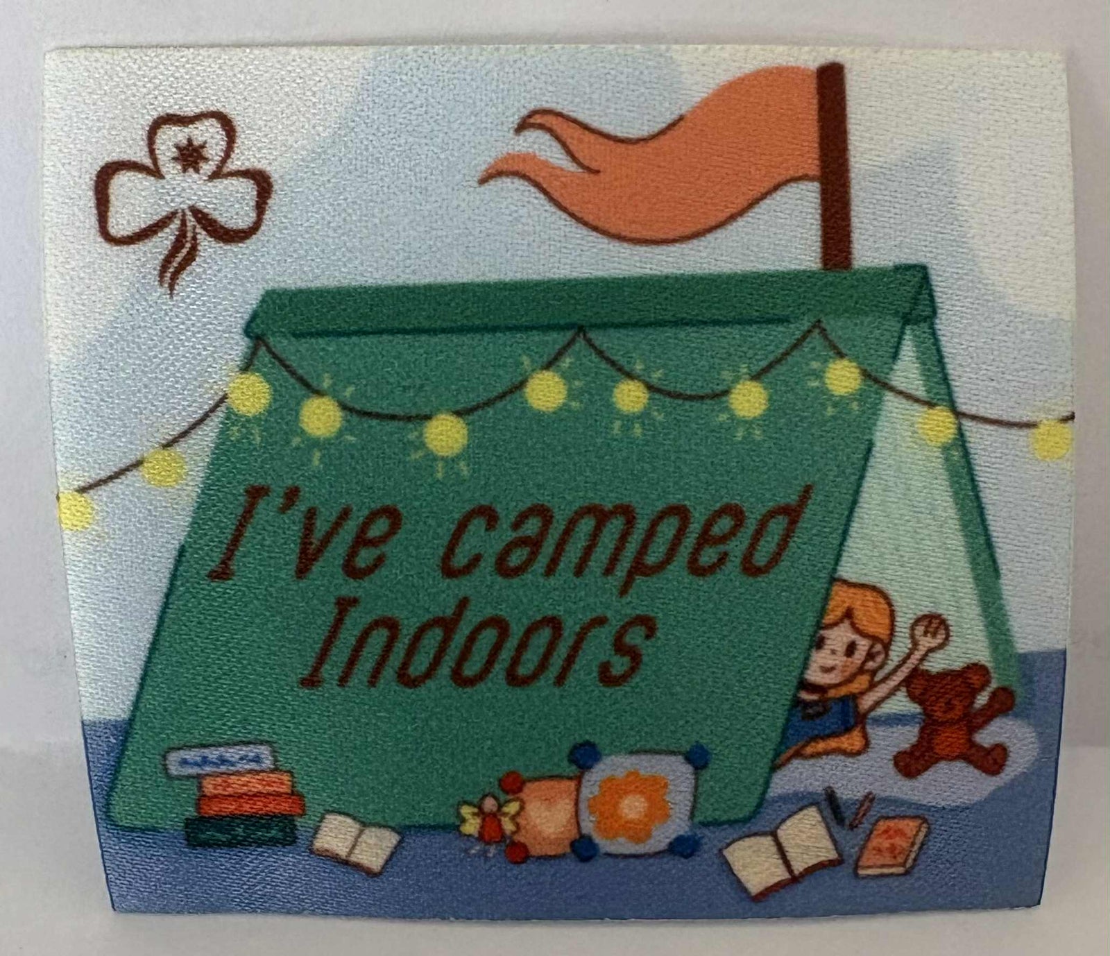 a square unbound badge with a tent, child, and teddy bear, featuring the text 'I've camped indoors'.