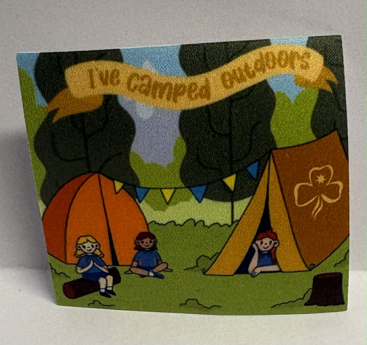 Square unbound badge with cartoon camping scene with girls and tents and 'I've camped out doors' text