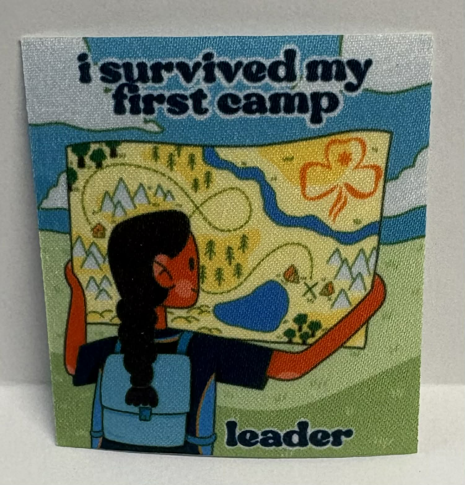 Square unbound badge with 'I Survived My First Camp' with a character holding a map and backpack.