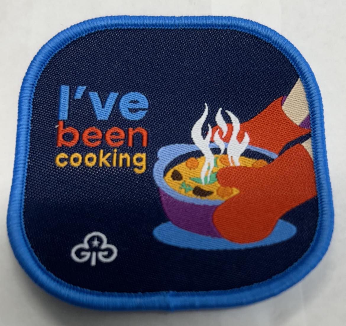 a square blanket with rounded corners with a pot with hands in pot holders with the words I've been cooking