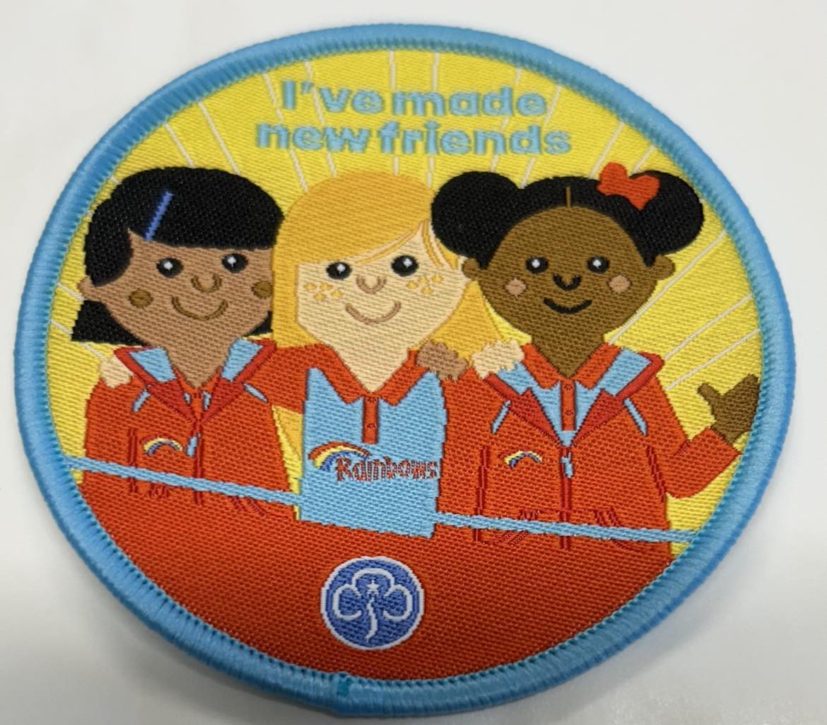 a round badge bound in light blue with three girls on the front with the words I've made new friends