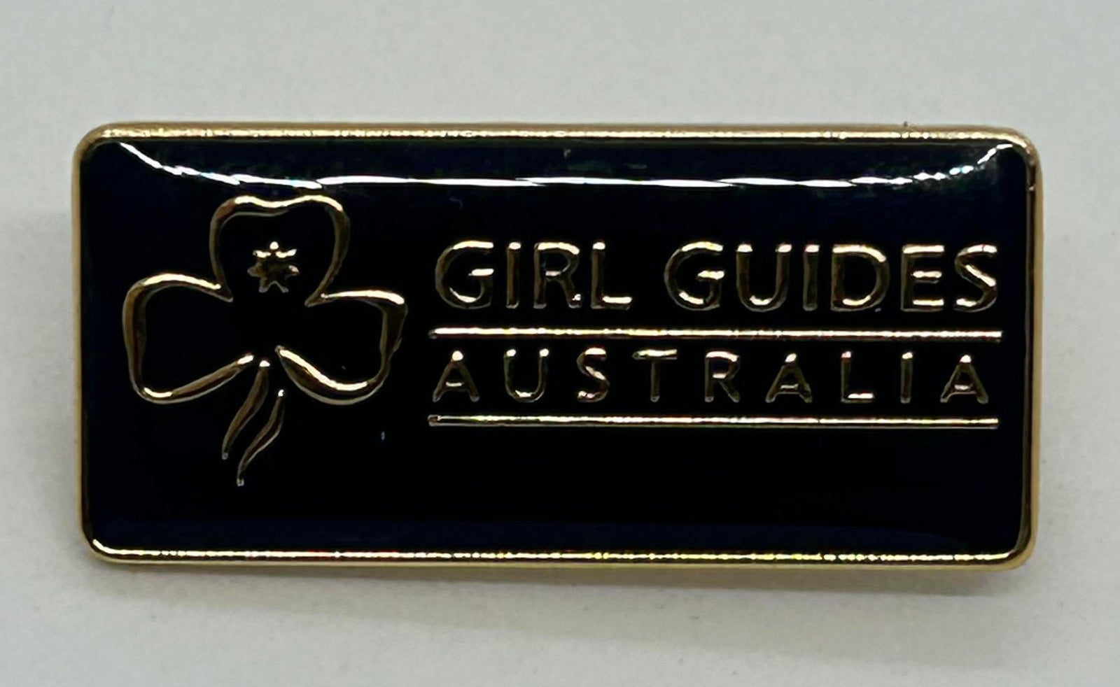 a mini metal pin with a navy blue enamel front with the trefoil and girl guides Australia in gold
