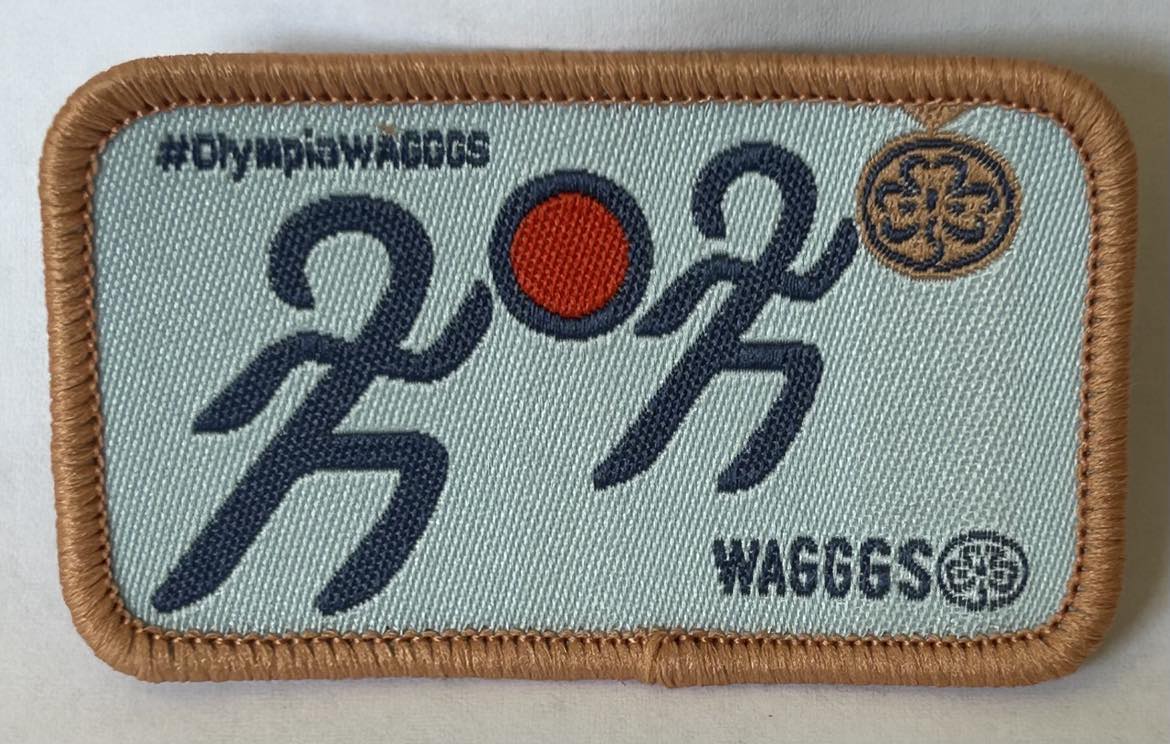 a rectangular badge bound in bronze with Olympia WAGGGS and two runners
