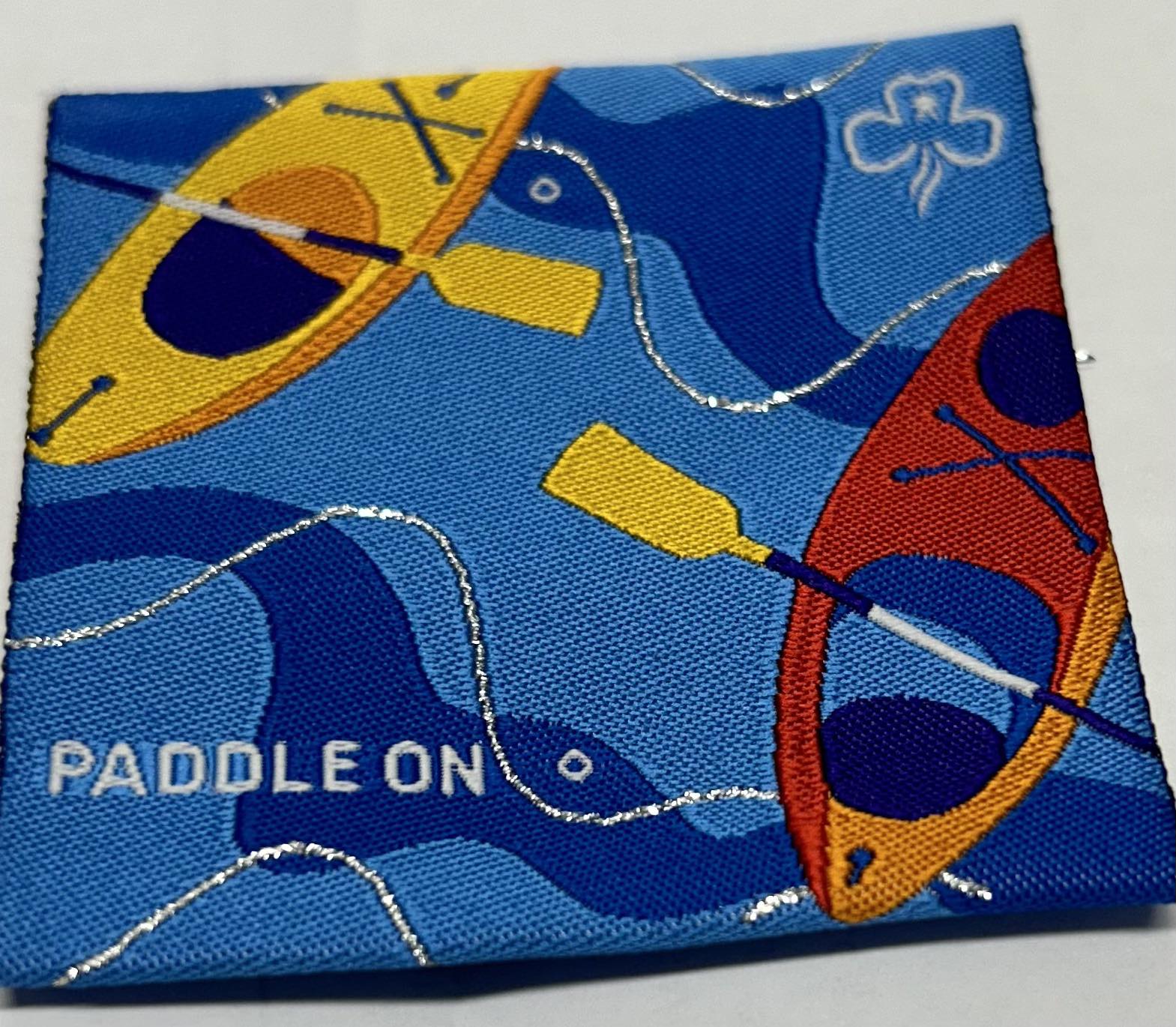 a square unbound blue badge with two kayaks with paddles