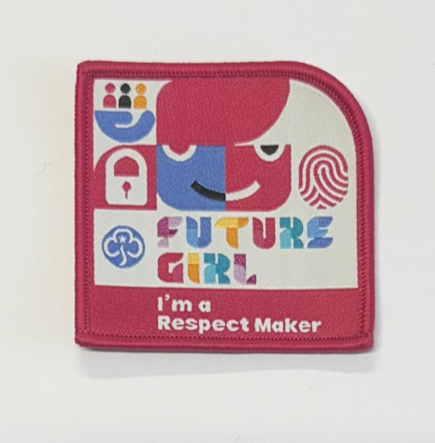 a square badge bound in pink with the words future girl I'm a respect maker with a face, finger print and people on it