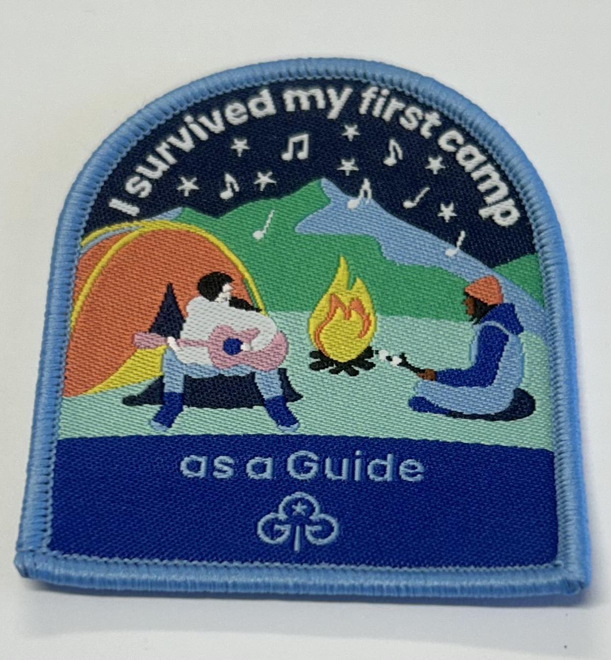 a bound badge that is square at the bottom and rounded at the top with two guides in a night time campfire setting