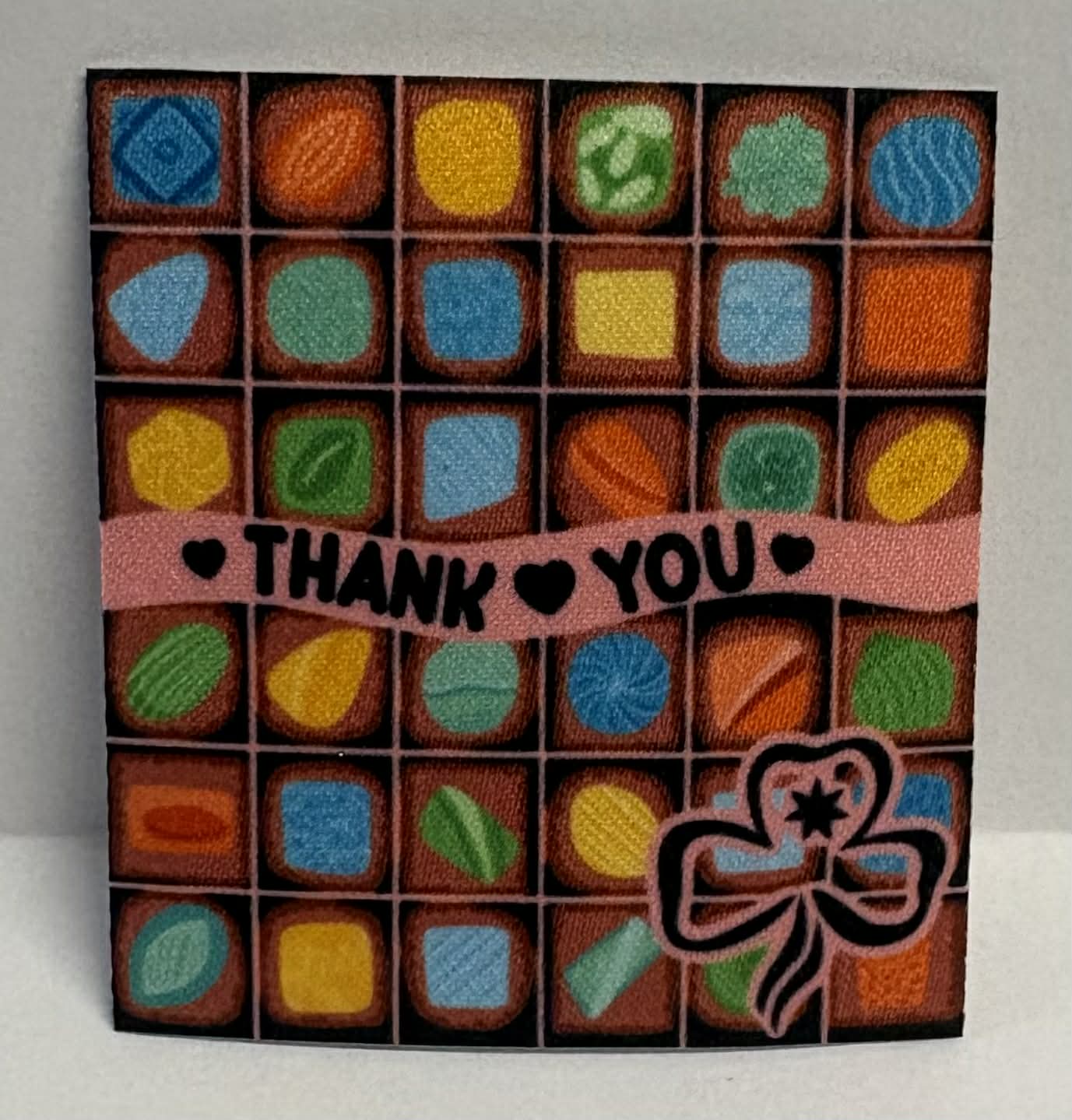 Square unbound badgewith chocolates in  square patterns and 'THANK YOU' text.