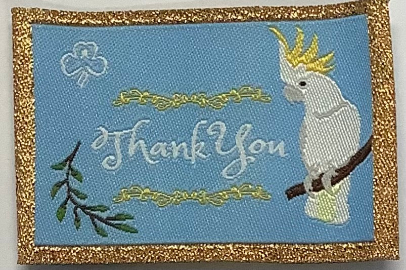 a square unbound badge that is light blue with gold edging with a shot cockatoo sitting on a branch