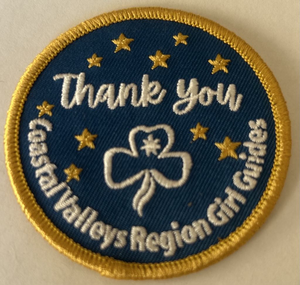 a round blue badge bound in yellow with the trefoil and stars and the words thank you coastal valleys region girl guides