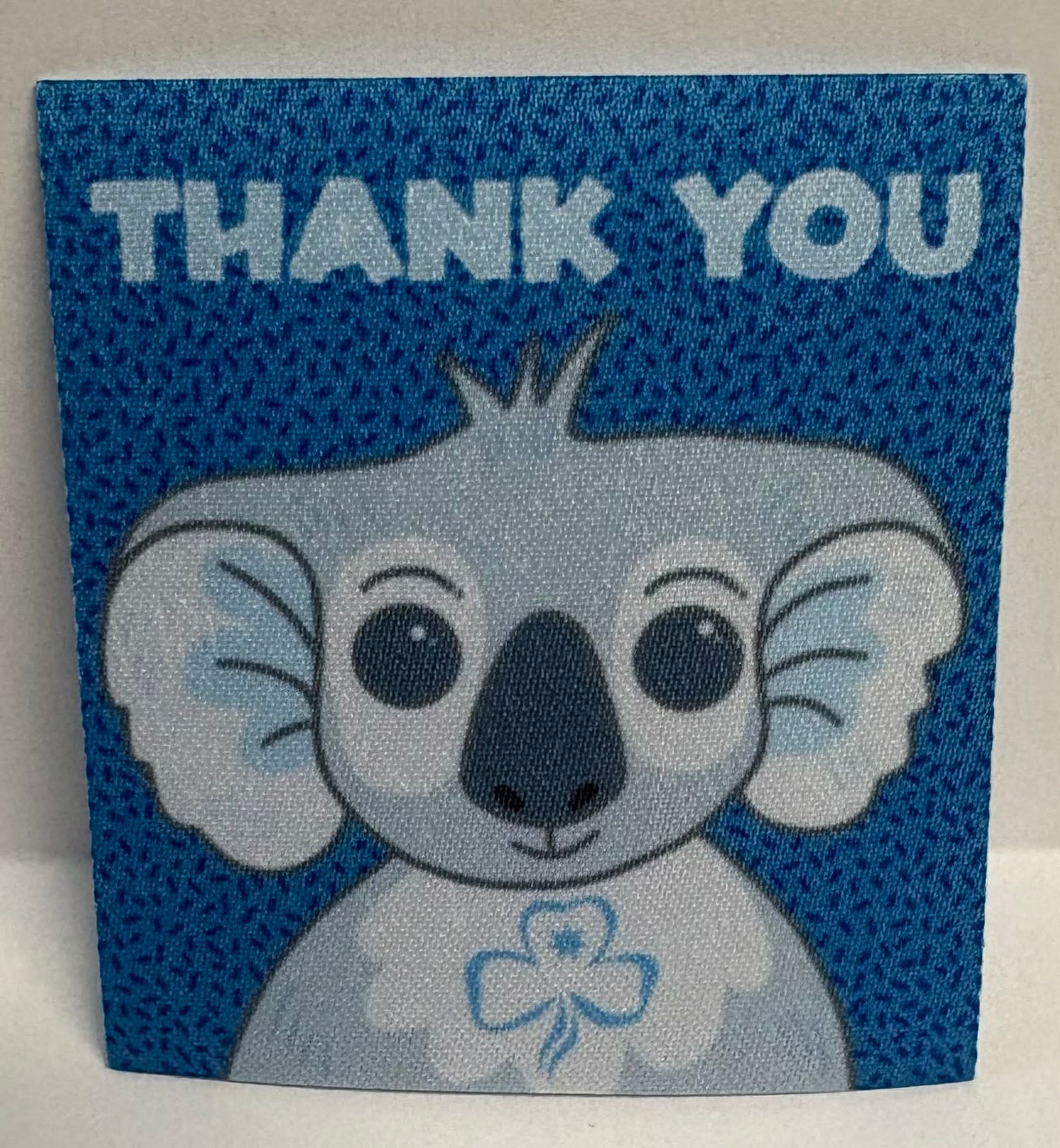 Square unbound badge with a koala face and 'THANK YOU' text on a blue patterned background