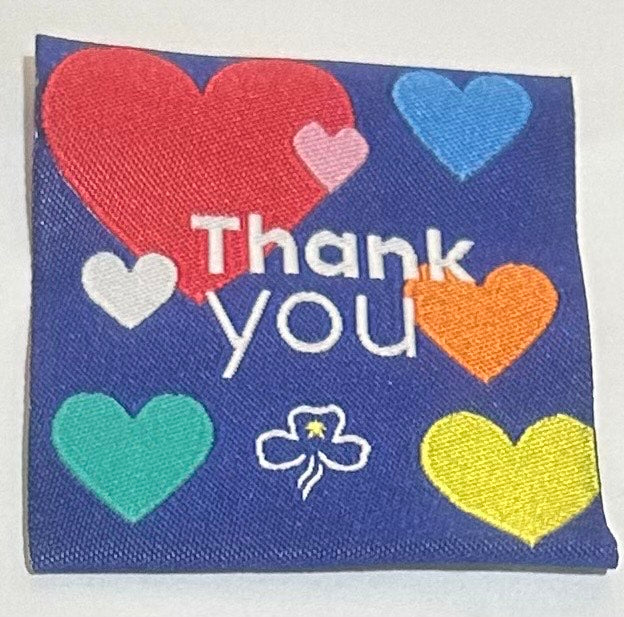 a square unbound badge with a dark blue background with coloured hearts and the words Thank You