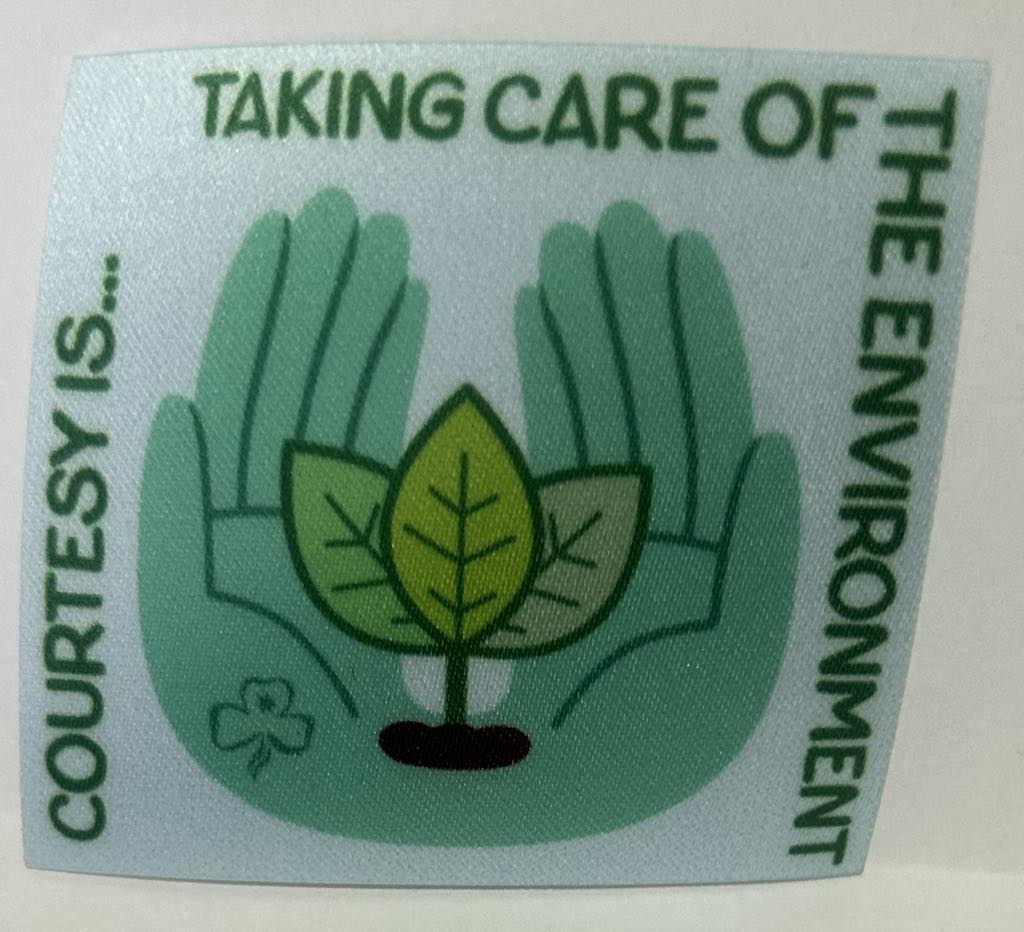 a square unbound badge on a light green background with two hands together holding a plant with the words courtesy is taking care of the environment