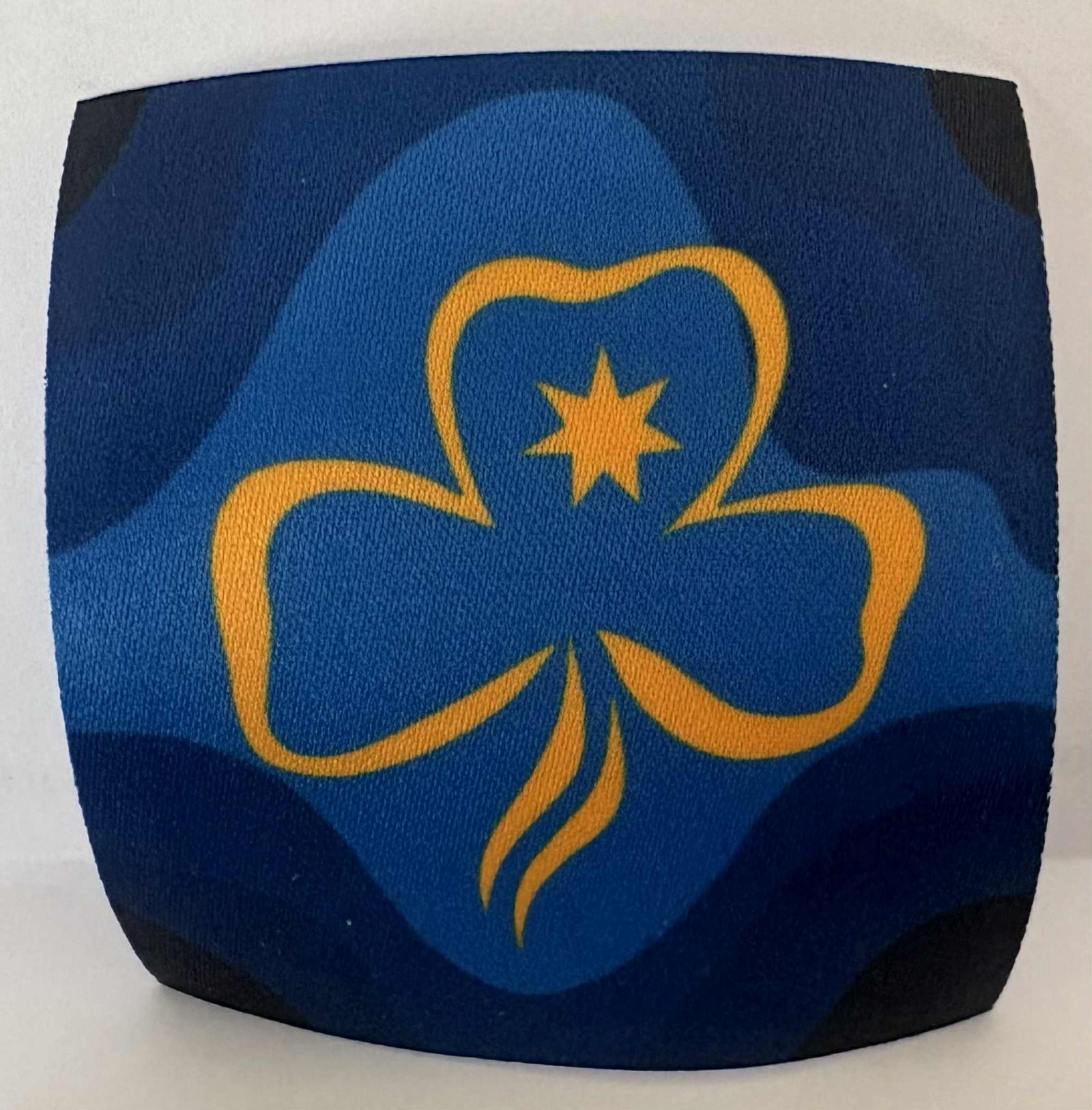 a square unbound badge with a yellow trefoil design on a blue background