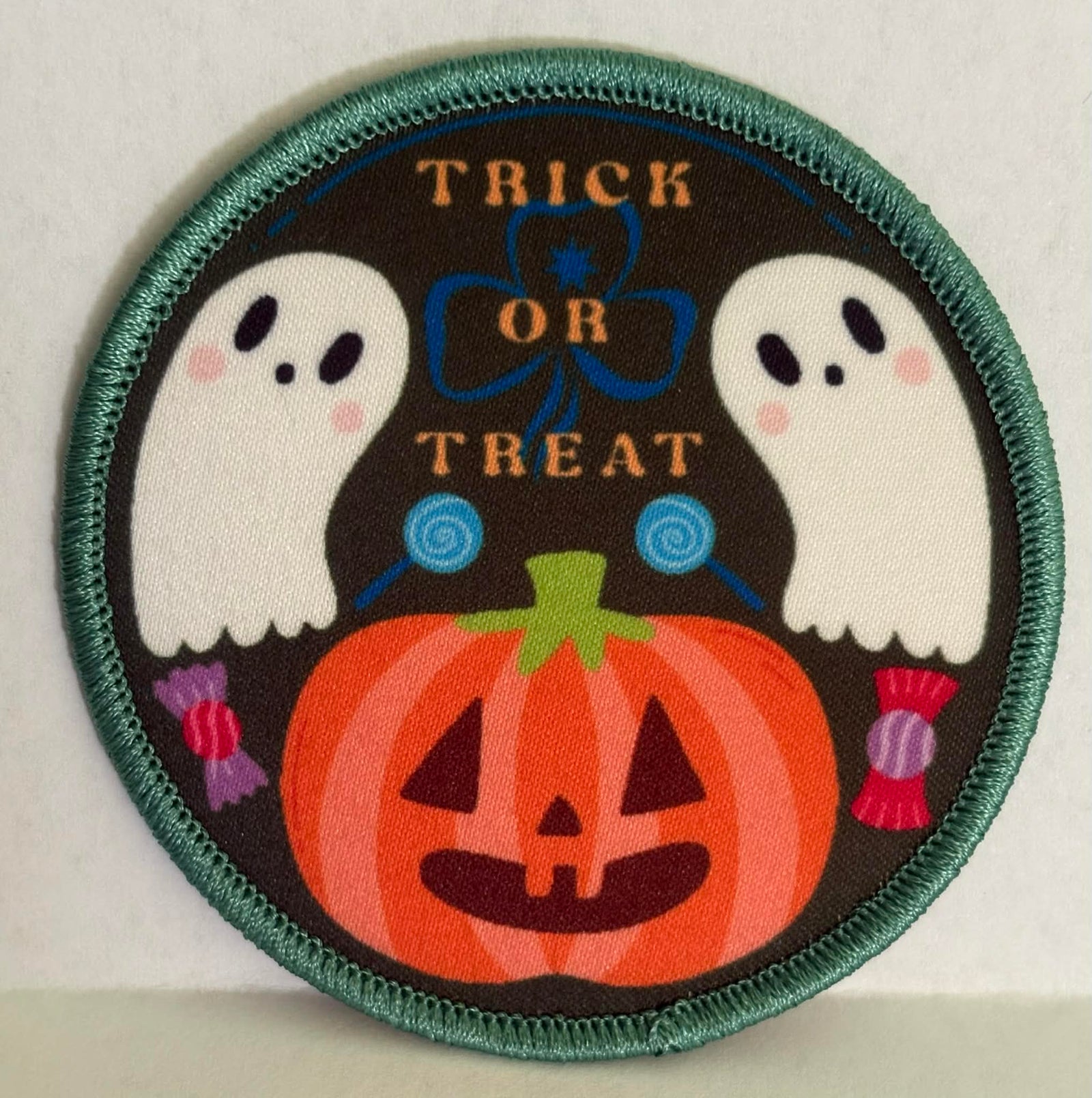 Halloween-themed round bound badge with ghosts, a pumpkin, and 'Trick or Treat' text on a dark background.