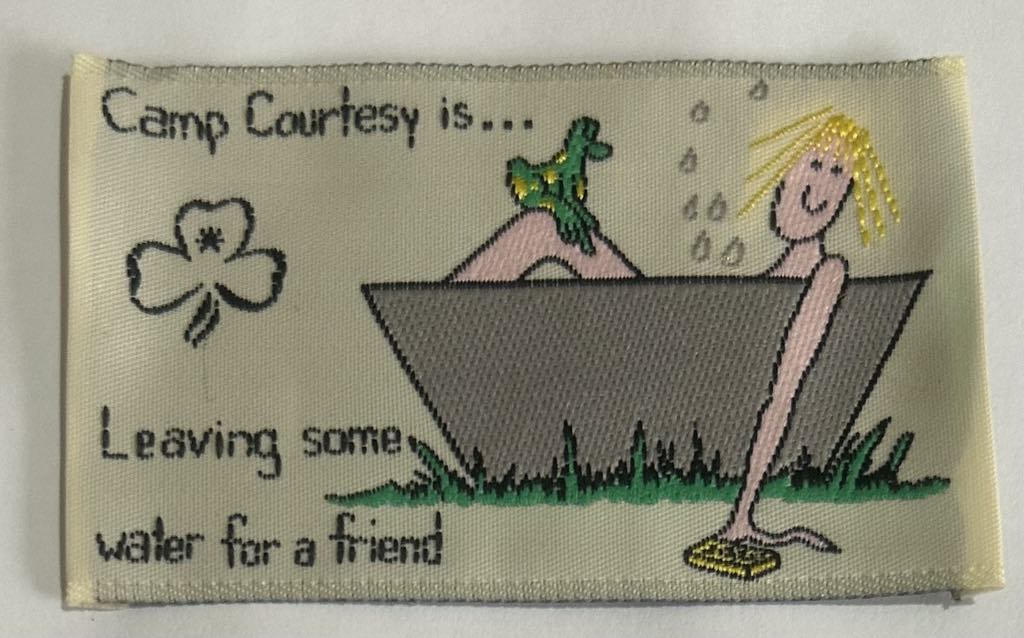 a rectangular unbound badge with a yellow background with a guide in a bath tub with the words camp courtesy is leaving some water for a friend