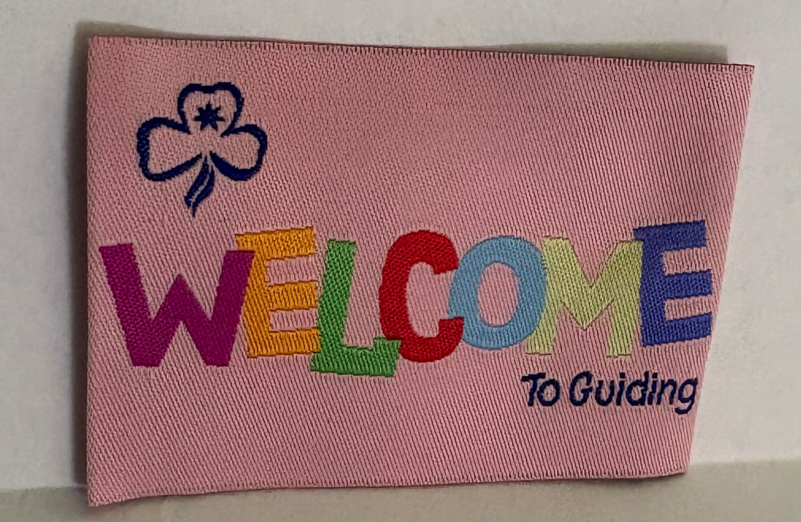 Pink unbound badge with colourful 'Welcome To Guiding' text and a trefoil