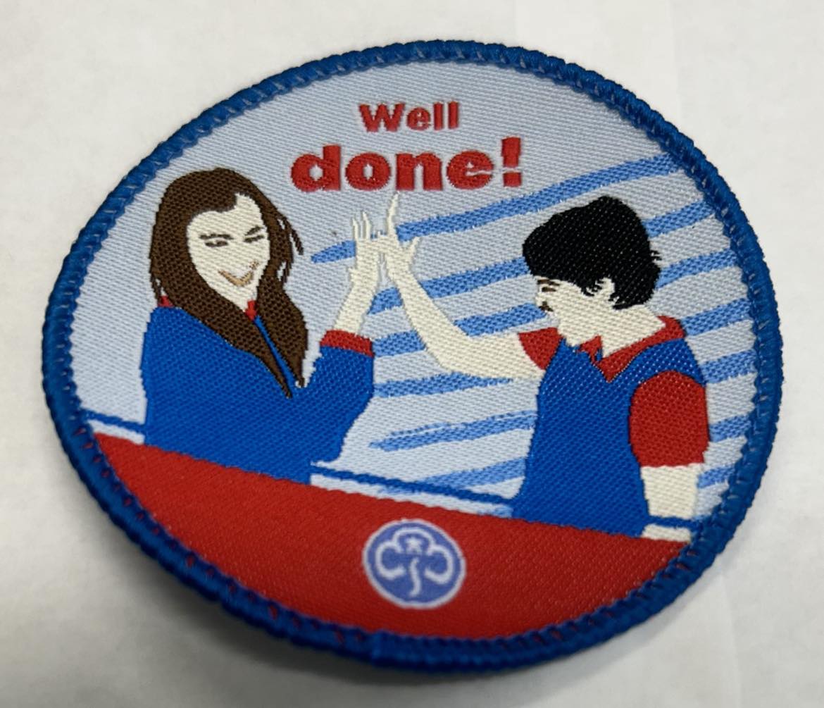 a round badge bound in blue with two girls high fiving